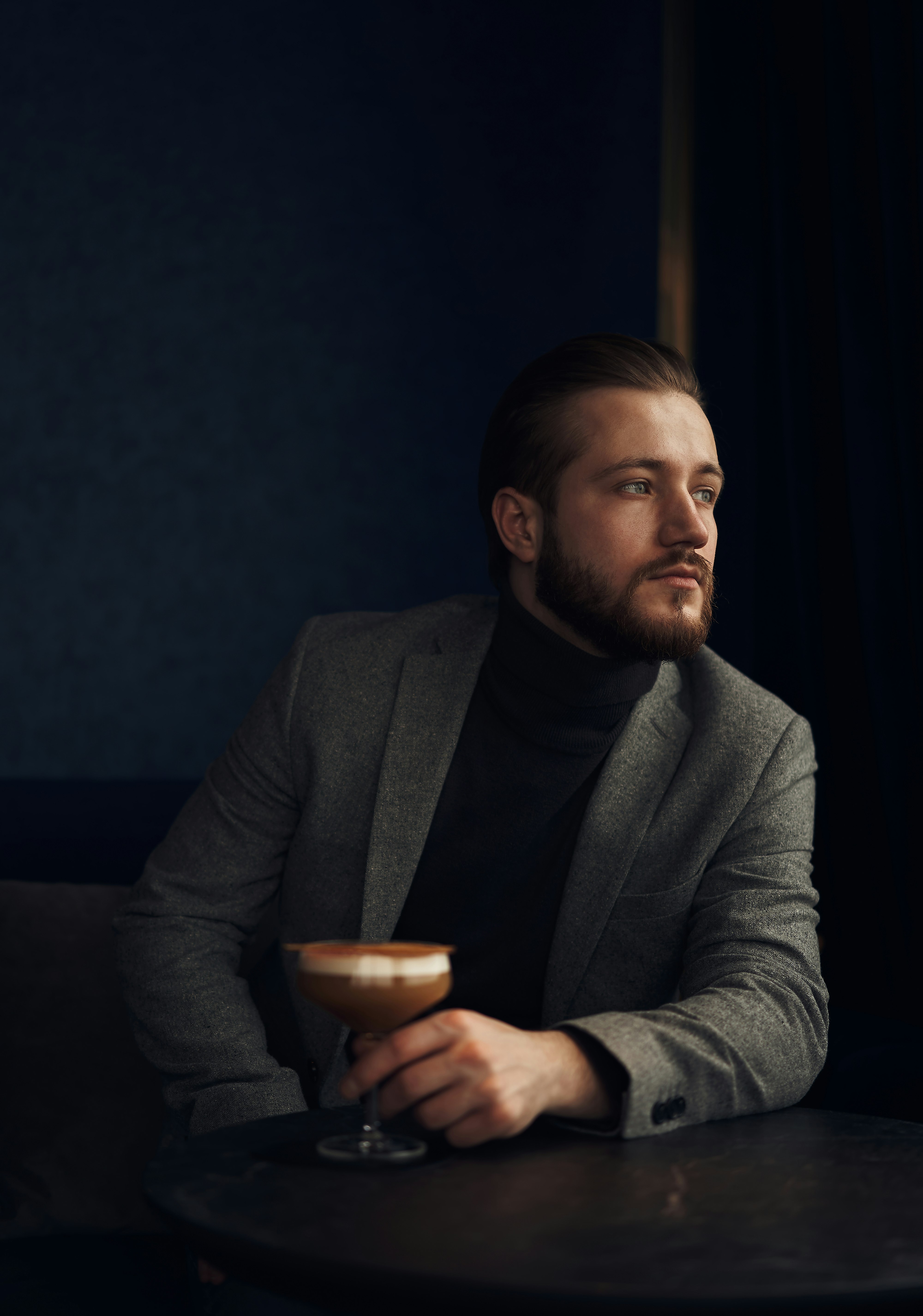 man in gray suit jacket holding brown ceramic mug